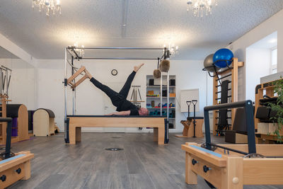 Male fitness pilates trainer shows exercises on special simulators. pilates stretch tables