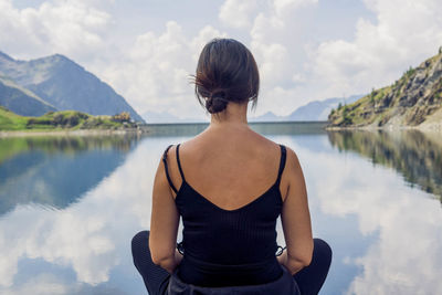 Rear view of woman looking at lake against sky