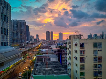 Modern buildings in city against sky during sunset