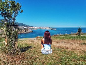 Rear view of woman looking at sea against clear sky