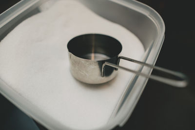 Measuring cup in plastic container filled with flour.