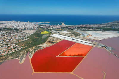 High angle view of sea by buildings against blue sky