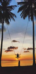 Silhouette girl on swing at sunset