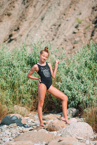 Full length of young woman sitting on rock