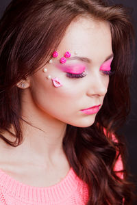 Close-up of beautiful young woman with make-up against gray background