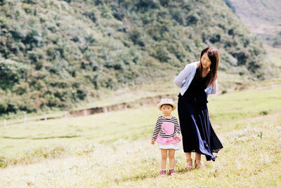 Rear view of mother and daughter walking on grass