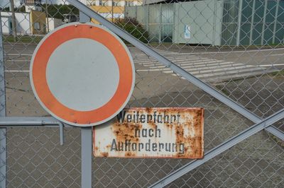 Close-up of road sign on fence