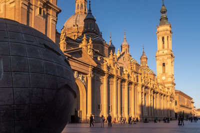 View of the cathedral of our lady of the pillar  in zaragoza, spain. people walk at sunset