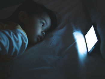 Close-up of toddler using mobile phone in dark