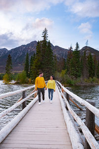 Rear view of people on footbridge against sky