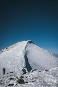 Low angle view of snowcapped mountain against clear blue sky