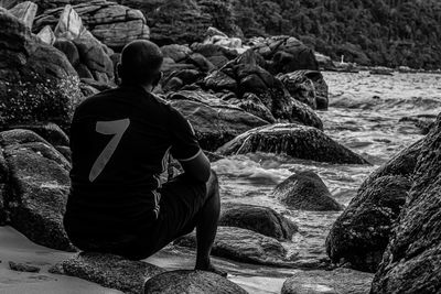 Rear view of men sitting on rock