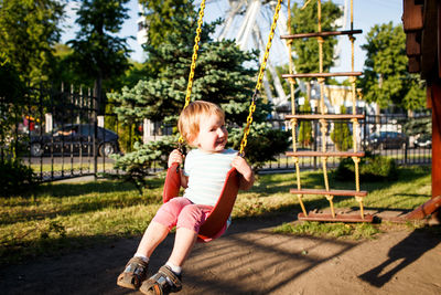 Full length portrait of girl on swing at park during sunny day