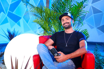 Portrait of young man sitting against plants