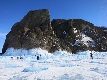 People on snowy field against mountains