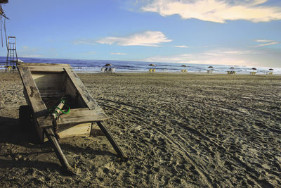 Wooden cart at beach against sky