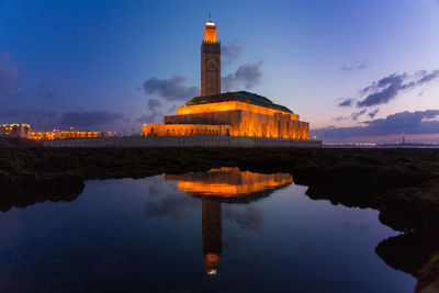 Reflection of illuminated building in water at sunset