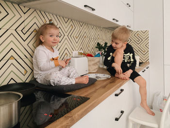 A view from a large angle of the children in the kitchen at home