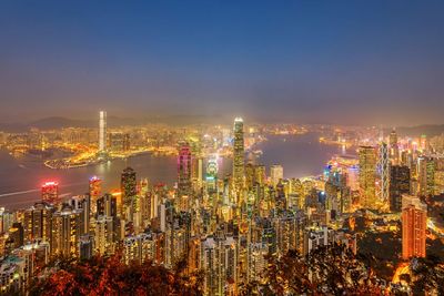 Illuminated modern buildings in city against sky at night