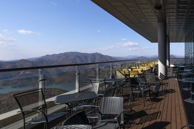 Empty chairs and tables at restaurant against sky