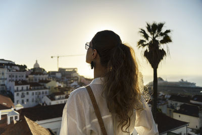 Young woman standing on rooftop in city during sunset