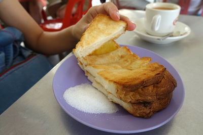 Cropped image of woman holding bread at restaurant table