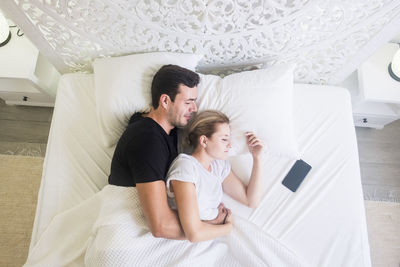 Directly above shot of couple lying on bed at home