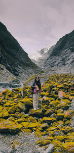 Rear view of woman standing on rock against sky