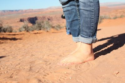 Low section of woman walking on sand