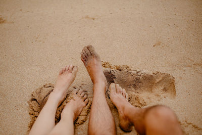 Low section of woman relaxing on sand at beach