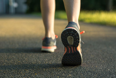 Low section of woman walking on road