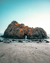 Rock formations on beach against clear sky