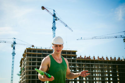 Portrait of man standing against construction buildings