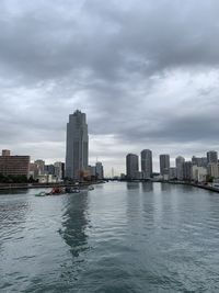 Sea by buildings in city against sky