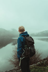 Rear view of man standing on mountain against clear sky