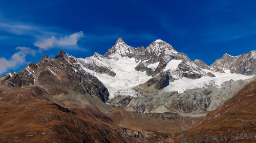 Scenic view of snowcapped mountains against blue sky