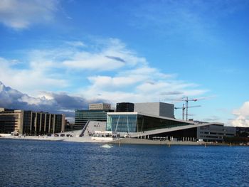 Buildings by river against blue sky