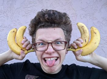 Portrait of teenage boy making a funny face and holding bananas by his head