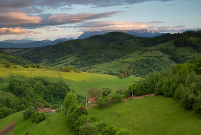 Scenic view of green landscape and mountains against sky