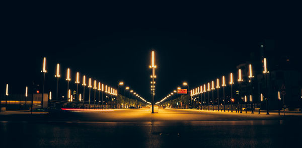 Illuminated bridge over river against sky at night