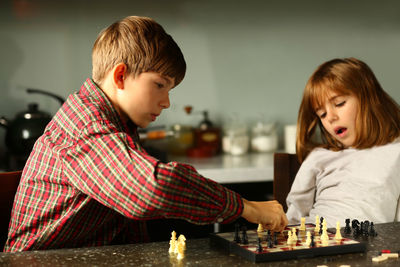 Children playing chess at home kitchen