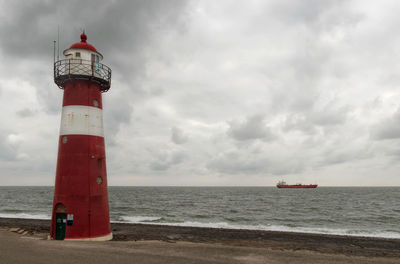 Lighthouse by sea against sky