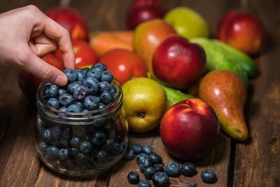 Close-up of hand holding berries with fruit on table