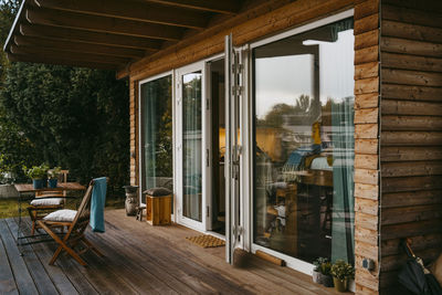 Wooden porch with chairs by glass door outside house