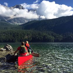 Men in boat on river against mountains