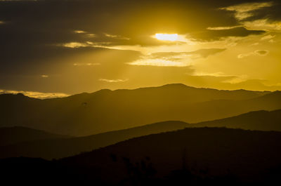 Scenic view of silhouette mountains against romantic sky at sunset