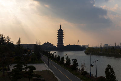 View of river by buildings against sky during sunset