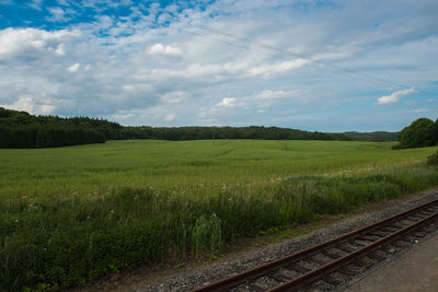 Railroad track amidst field against sky