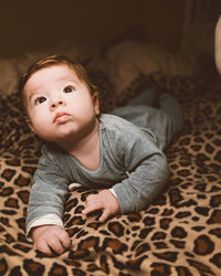 Portrait of cute baby boy lying on bed at home