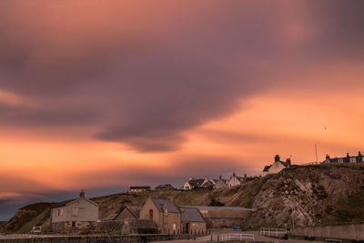 Buildings against cloudy sky at sunset